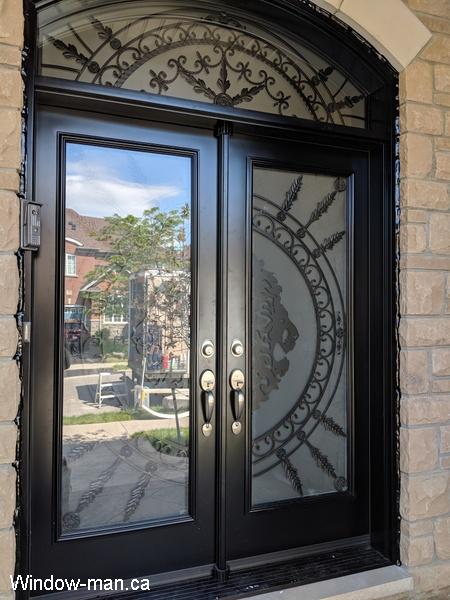 Double entry insulated front exterior doors. Black. Forest King Lions iron glass design. Matching round top arch head transom